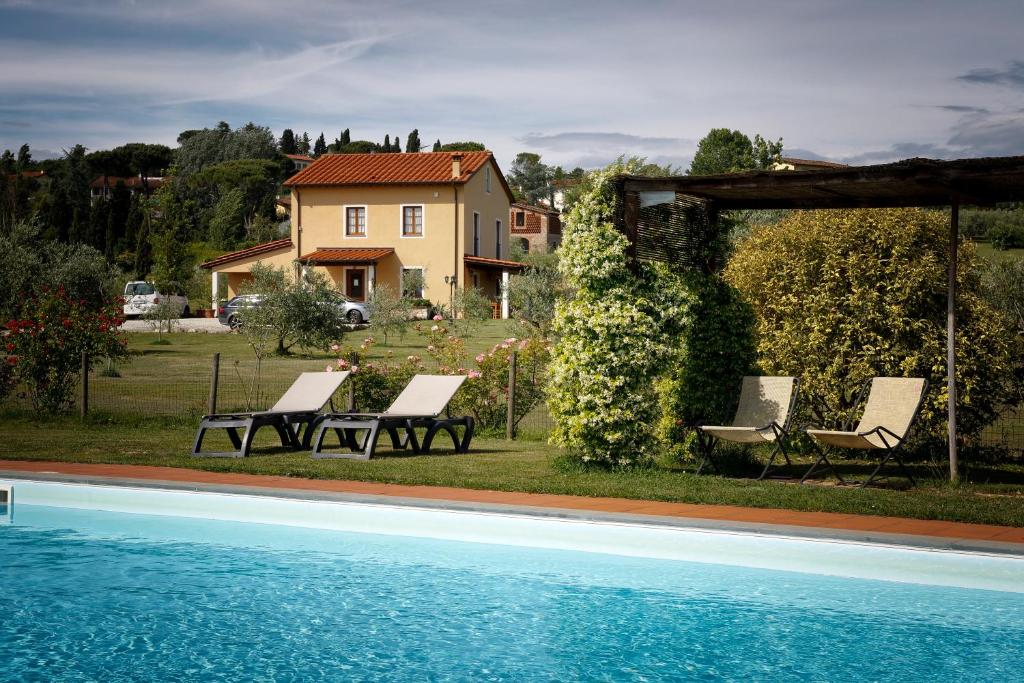 a pool with chairs and a house in the background at Agriturismo Ai Linchi in Lucca