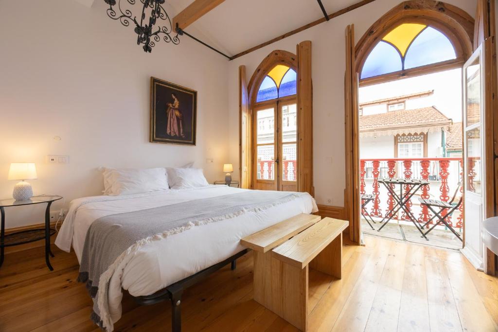 a bedroom with a bed and a large window at Casa da Baixa by PURUS in Coimbra