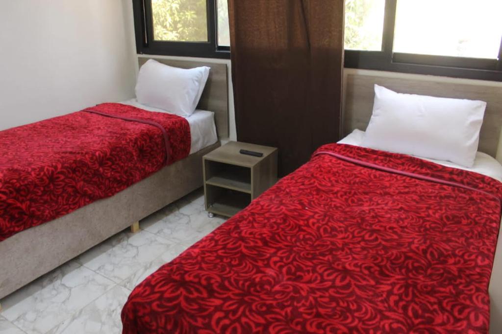 a bedroom with two beds and a red blanket at فندق النادي in Aswan