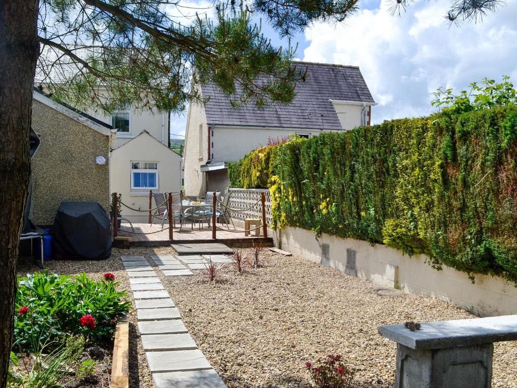 a garden with a bench and a hedge at Sonny Cottage in Glanamman