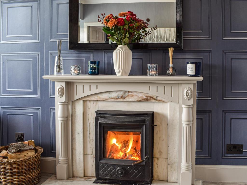 a fireplace with a vase of flowers on top of it at Dothan Farm Cottage in Cardenden