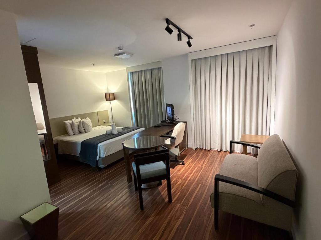 a hotel room with a bed and a table and chairs at Hotel Alameda Campinas Paulista in São Paulo
