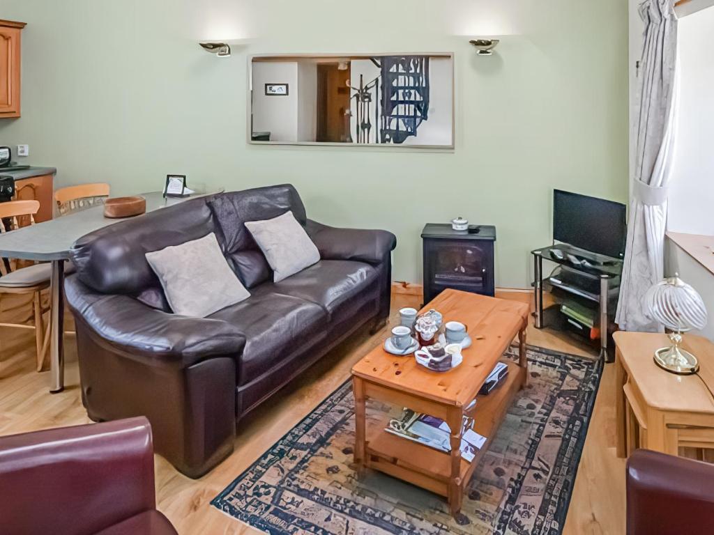 a living room with a leather couch and a table at Cosy Neuk - Uk51345 in Peebles