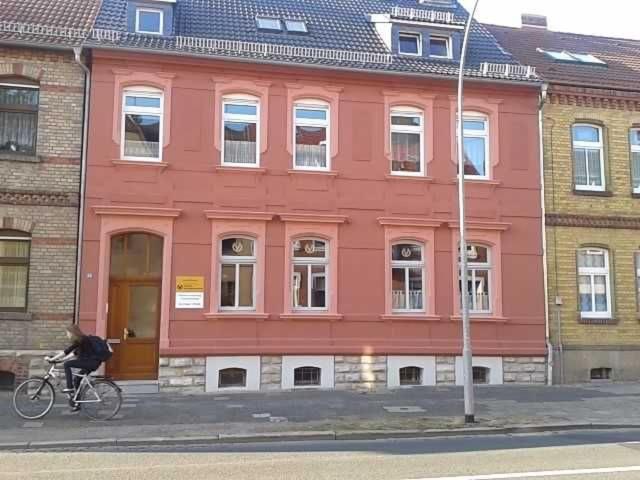 a person riding a bike in front of a pink building at Ferienwohnung Gleißner Hartmann in Sangerhausen