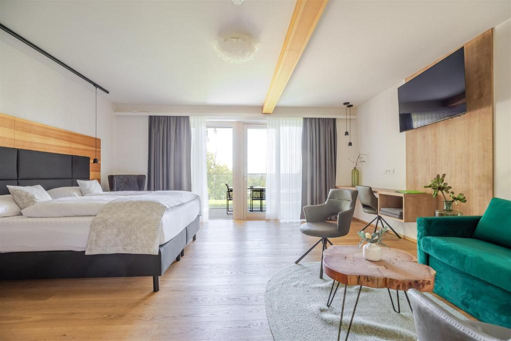 ein Schlafzimmer mit einem Bett und einer grünen Couch in der Unterkunft Hotel Ottenstein - Das Wohlfühlhotel in Rastenfeld