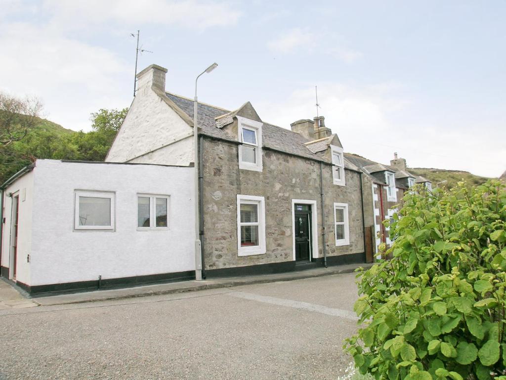 a white house with a brick building at Boatmans Cottage - 27787 in Portessie