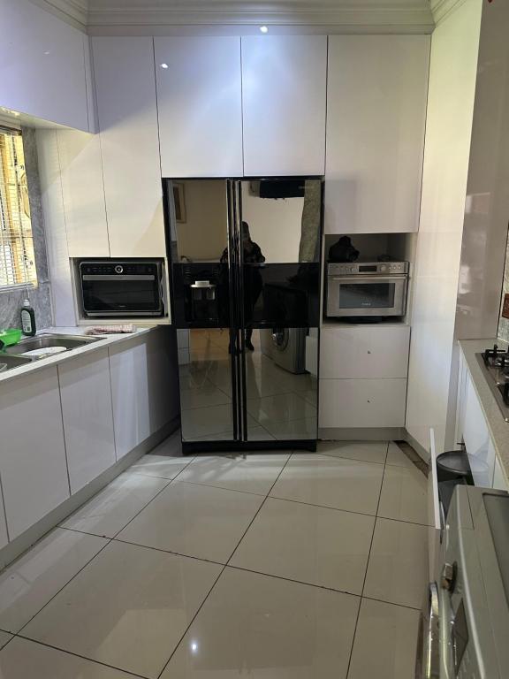 a kitchen with white cabinets and a glass refrigerator at Royaltics Lumina house in Weltevredenpark