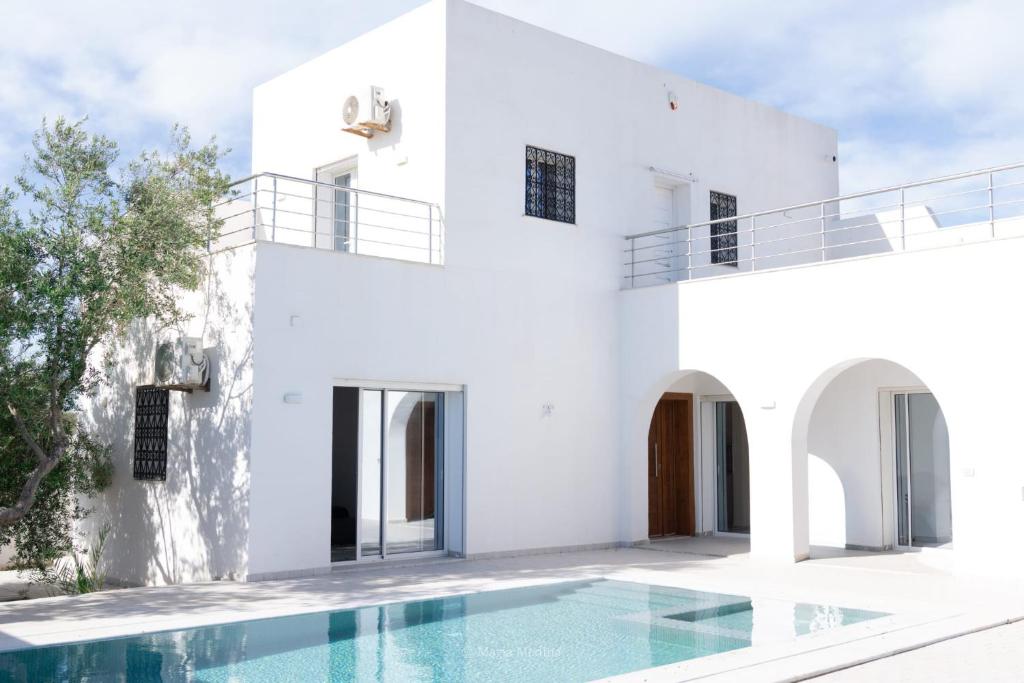 a white house with a swimming pool in front of it at Villa Zain in Houmt Souk
