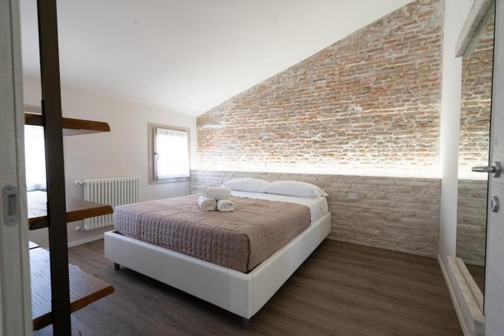 a bedroom with a bed with a brick wall at Chioggia Rooms in Chioggia