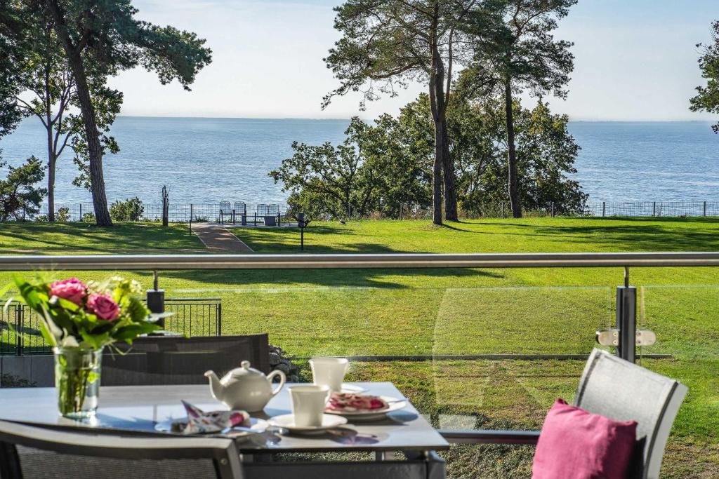 a table with a vase of flowers on a balcony with the ocean at Appartement Haffperle-Oase am Haff in Garz