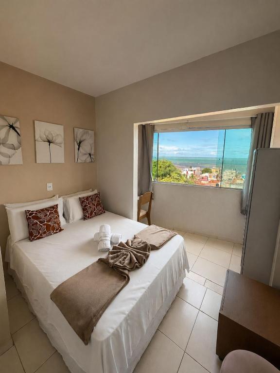 a bedroom with a large white bed with a large window at Pousada Boa Vista in Maragogi