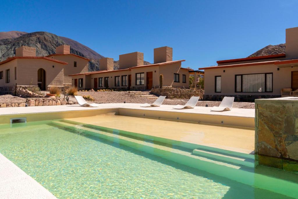 a swimming pool with chairs in front of a house at Alma de Purmamarca in Purmamarca