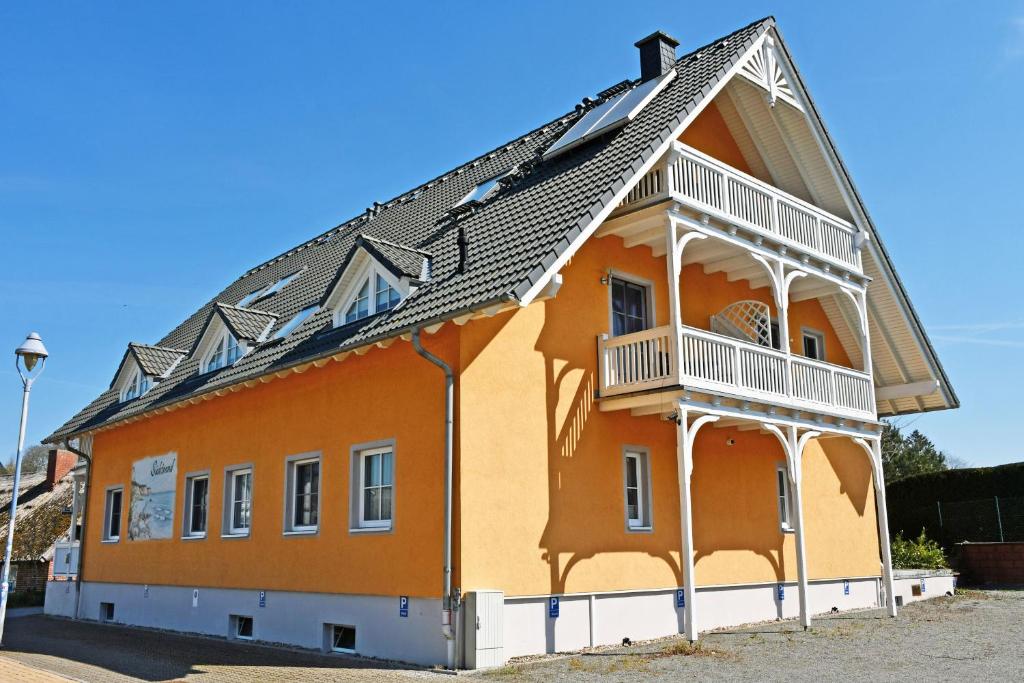 a large orange building with a balcony at Hotel Sonnenklahr mit Pool in Göhren
