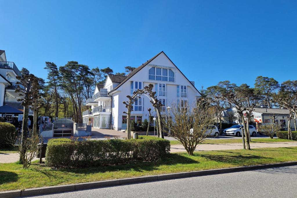 a white house on a street with trees and cars at Ferienwohnung Graugans in Baabe