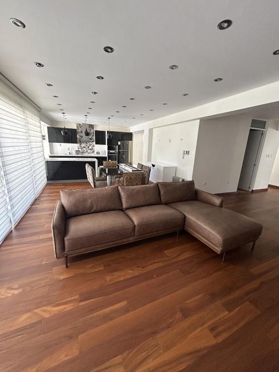 a living room with a brown couch and a kitchen at Luxury apartment with park views in Huancavelica