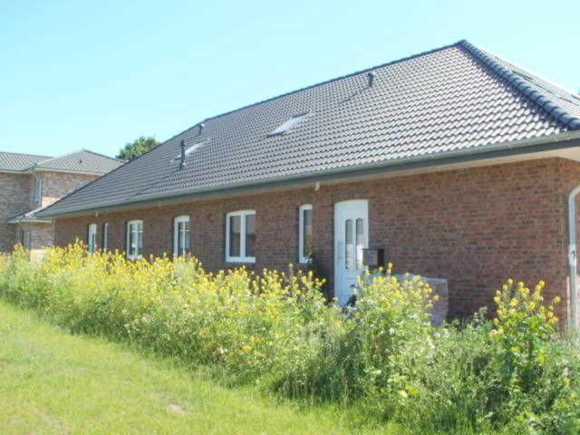 a red brick house with a bunch of flowers in front of it at Scholz-Riewerts - gemütliches Apartment mit Küche für 2 Personen in Silberstedt