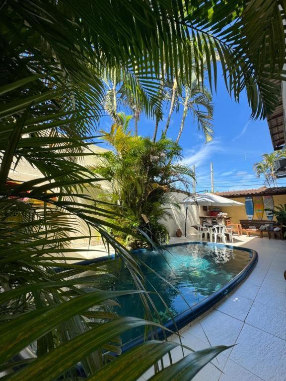a swimming pool with palm trees in front of a house at Pousada Casa Meraki in São Sebastião