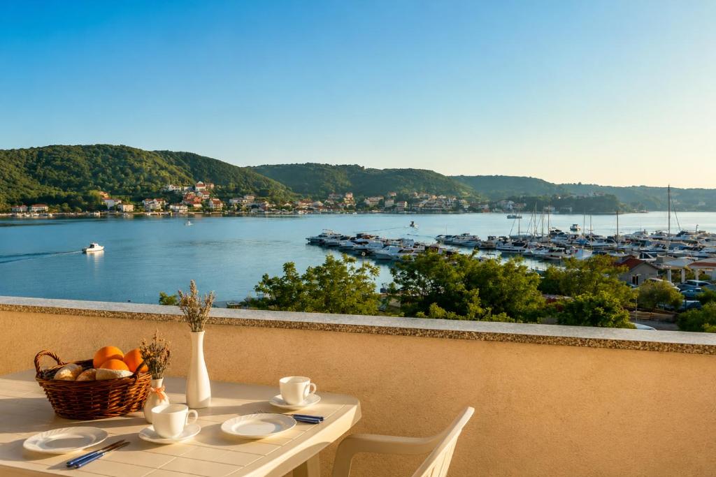 a table with a basket of fruit and a view of a harbor at Pljesa Apartments -Meerblick mit Terrasse & Grill by rentyourhome24 in Supetarska Draga