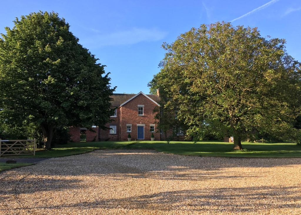 a brick house with two trees in front of it at College Farm in Brackley