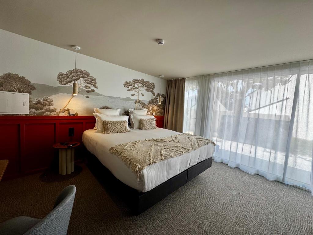 a bedroom with a bed and a large window at Hôtel des quatre saisons in Guérande