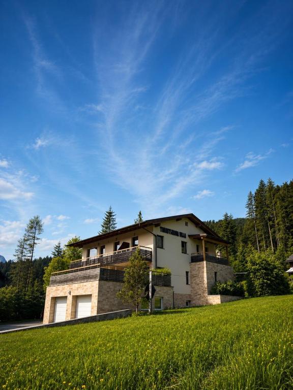 a house on a hill with a green field at Transylvania Villa & Spa in Gosau