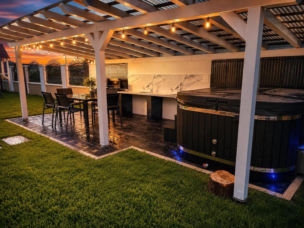 eine Terrasse mit Tisch und Grill unter einer Pergola in der Unterkunft Vila MEM in Sebeş
