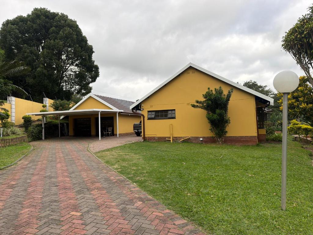 a yellow house with a brick driveway at The Cozy Corner House in Durban