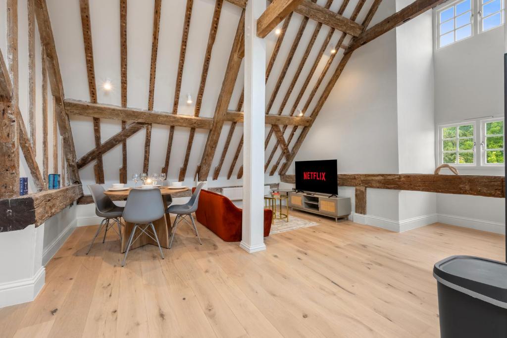 a dining room with a table and a tv in a loft at Modern & Historic Duplex Flat Riverside in Godalming