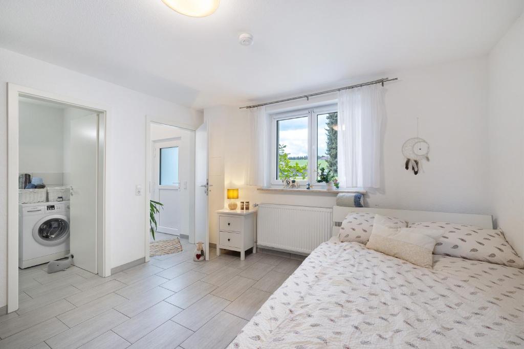 a white bedroom with a bed and a washing machine at Gemütliche Einliegerwohnung in Gomadingen