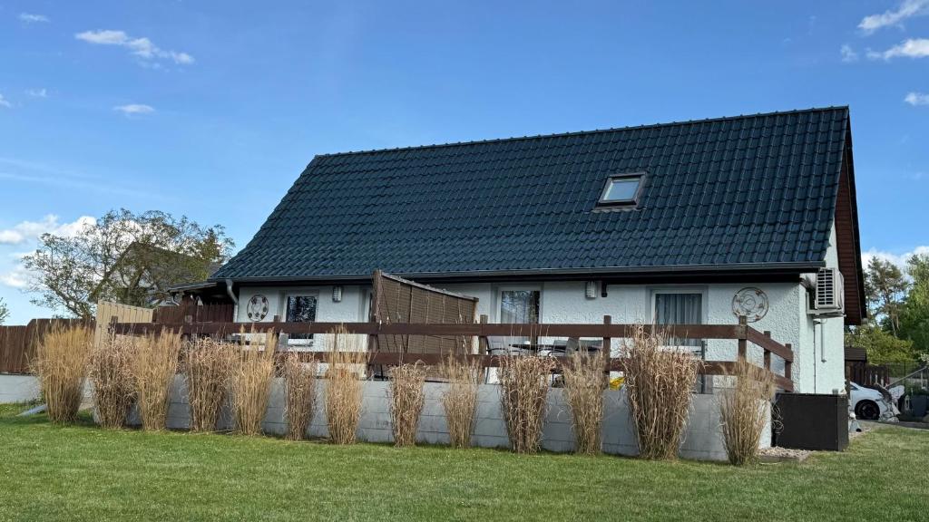 a house with a black roof and a fence at FEWO Am Haussee Feldberger Seenlandschaft in Feldberg