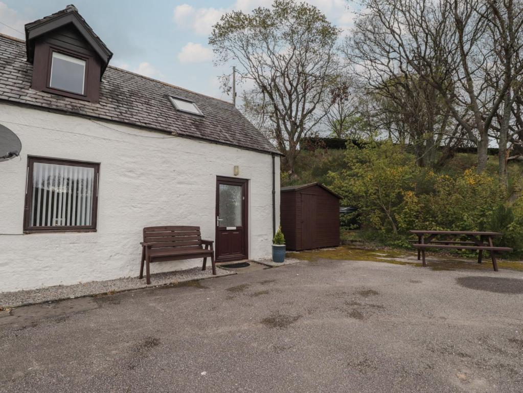 a white house with a bench and a table at 3 Bruaich Cottages in Strathpeffer