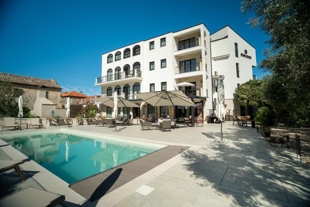a hotel with a swimming pool in front of a building at Hotel Stari Dvor in Ugljan