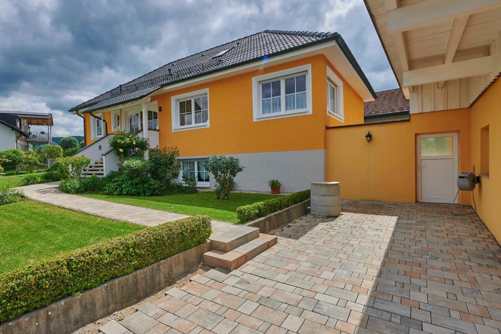 a yellow house with a brick driveway at FEWO Geisbergblick in Zeegendorf
