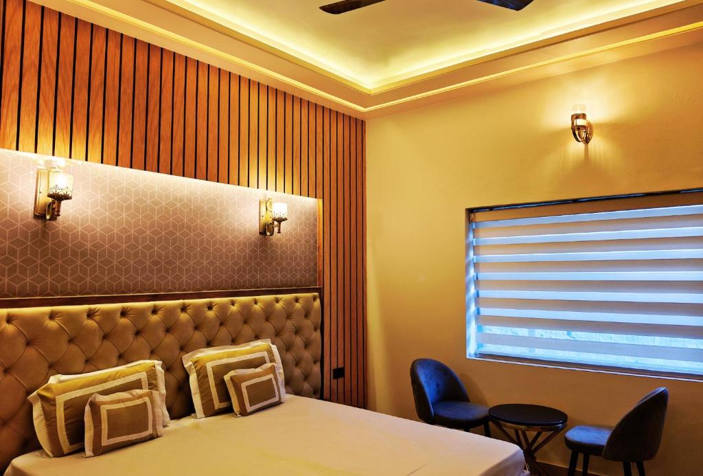 a room with a bed and two chairs and a window at Shakti Resort in Behror