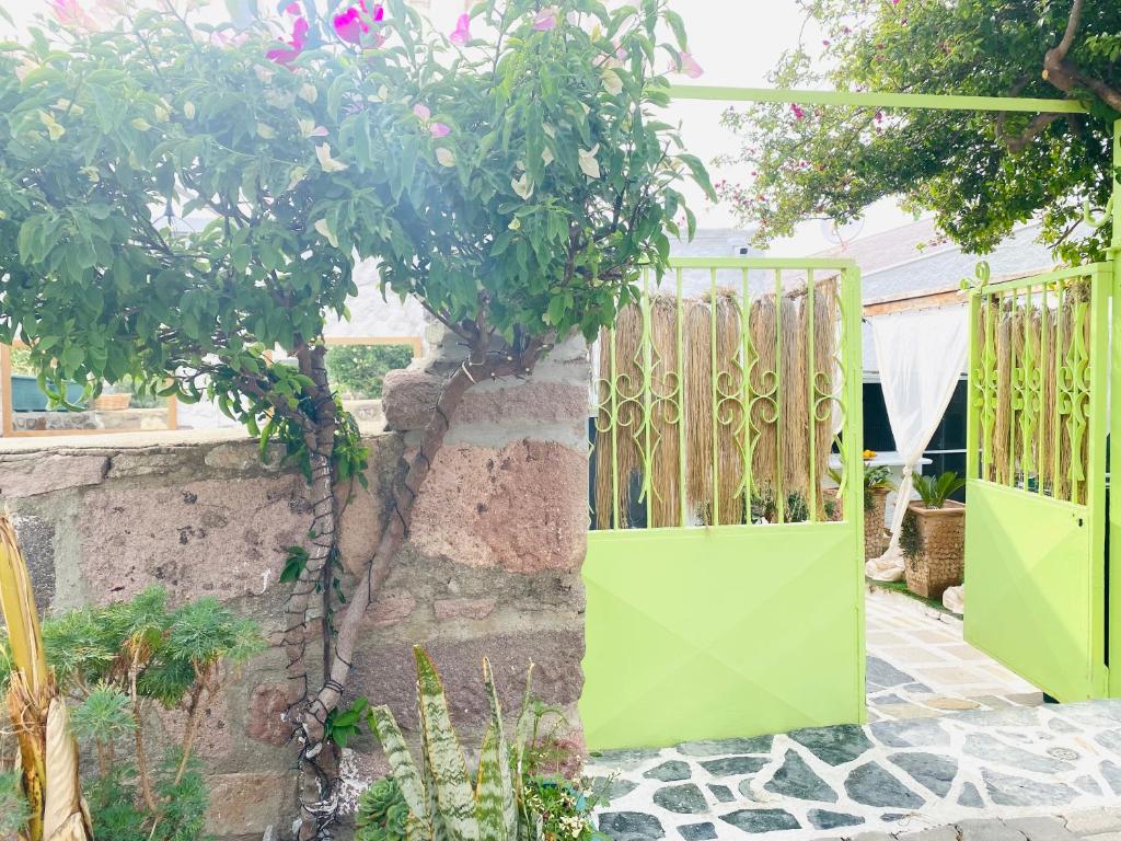a green gate in a garden with a tree at BadeHan Guest House in Çeşme