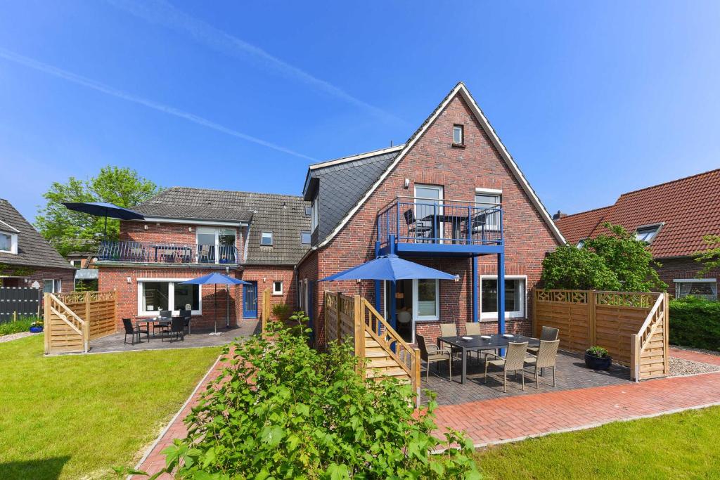 a house with a patio with tables and umbrellas at Ferienwohnungen Blaues Haus in Bensersiel