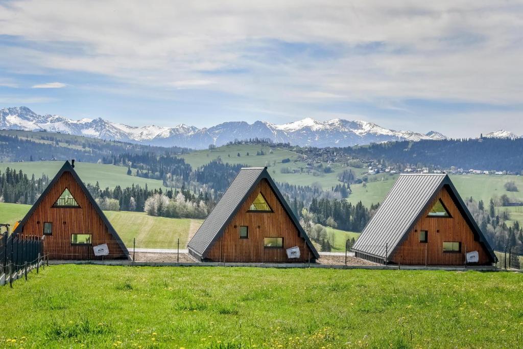 a group of barns in a field with mountains in the background at Maruszyna Resort & SPA in Zakopane
