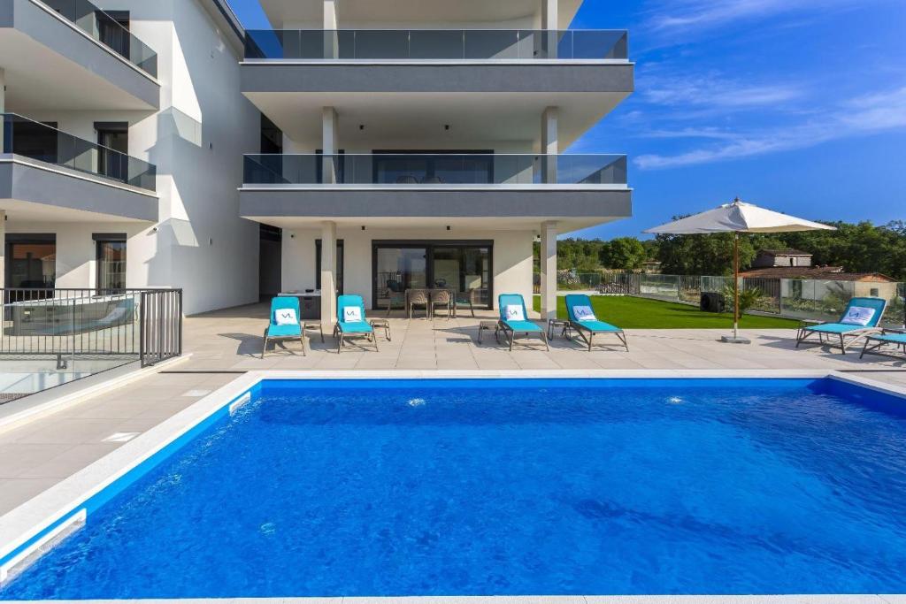 a villa with a swimming pool and a house at Apartments Luna in Malinska