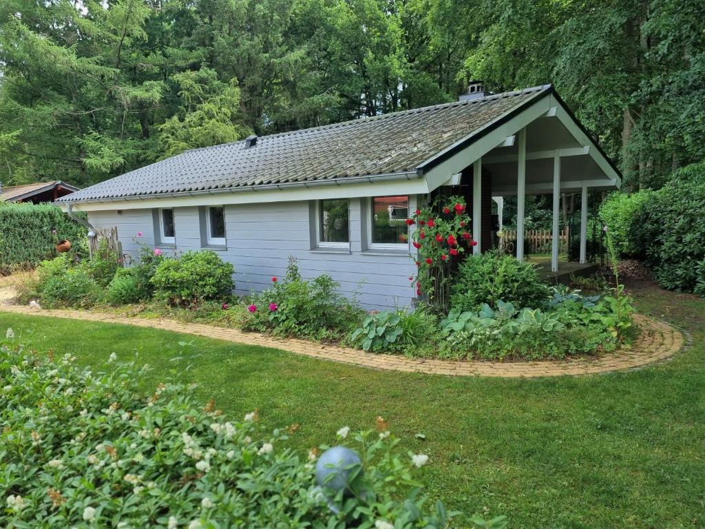a small white house with a garden in the yard at Ferienhaus Paulsen - gemütliches Häuschen mit vollständig eingezäuntem Garten und Kamin in Silberstedt