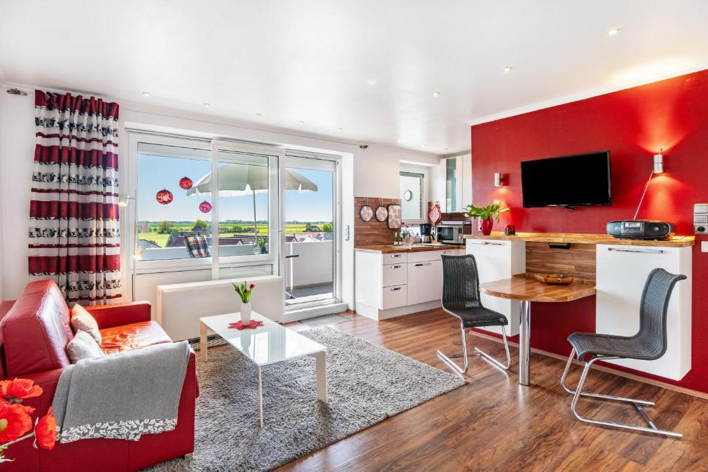 a kitchen and living room with a red wall at Apartment Korthals 42 in Wangerland