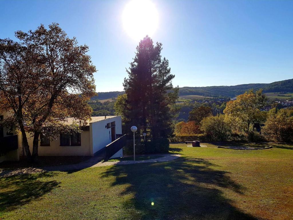 a house with a tree and the sun in the sky at Berg-Bungalows Leinleitertal in Heiligenstadt