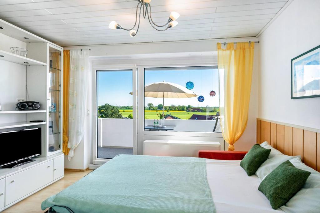 a bedroom with a bed and a balcony with an umbrella at Apartment Korthals 41 in Wangerland