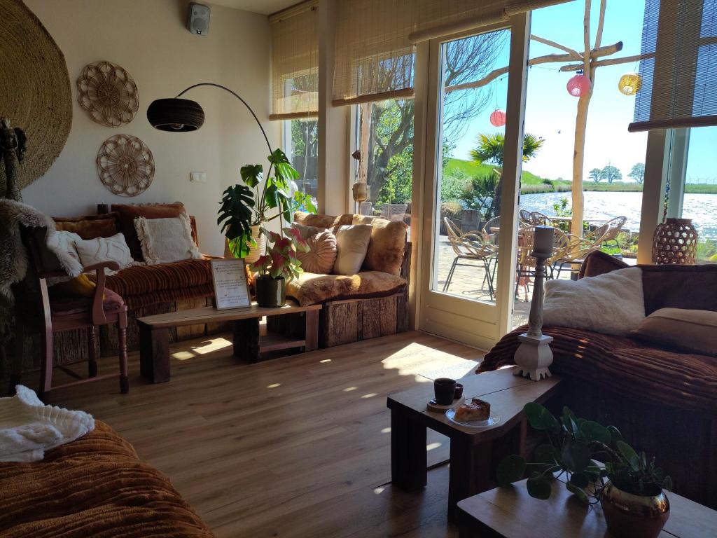 a living room with couches and tables and windows at HotelPension van Ewijcksluis in Anna Paulowna