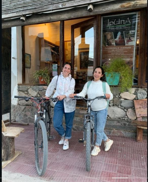 a man and a woman holding bikes in front of a store at Cafayate Backpackers in Cafayate