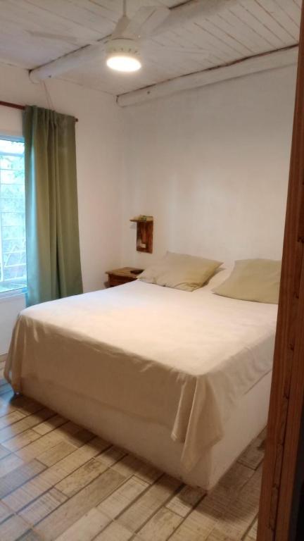 a bedroom with a large white bed and a window at Casa Quinta Doña María in Concepción del Uruguay