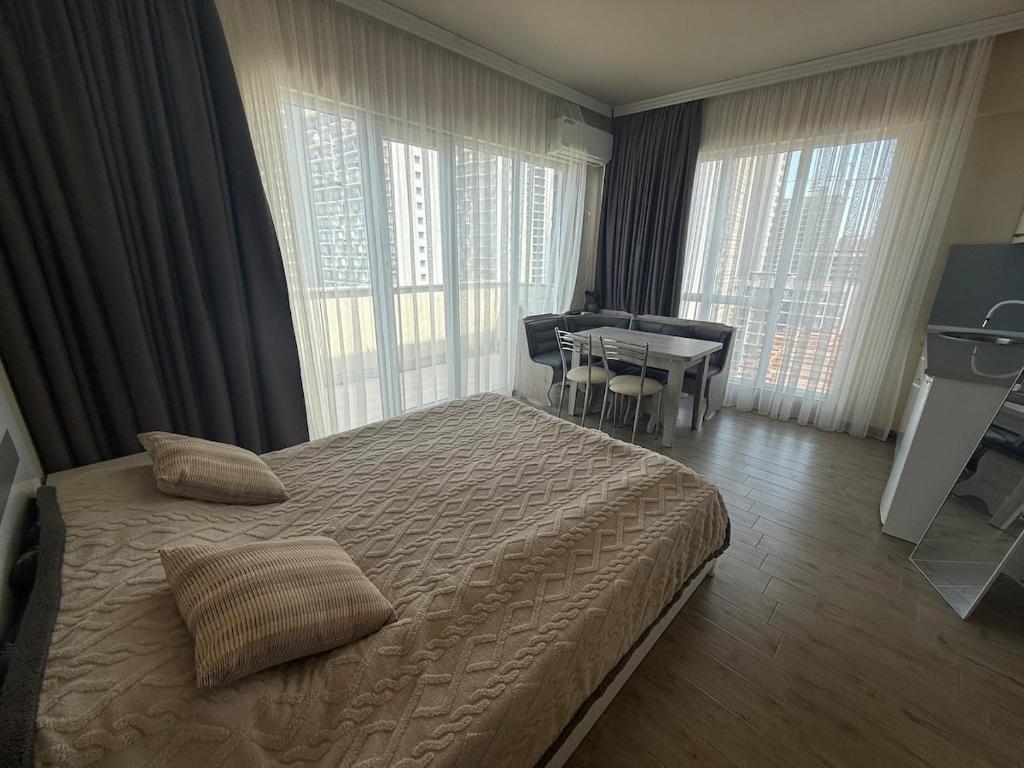 a bedroom with a bed and a table and windows at Apartment on Angisa, 78 in Batumi