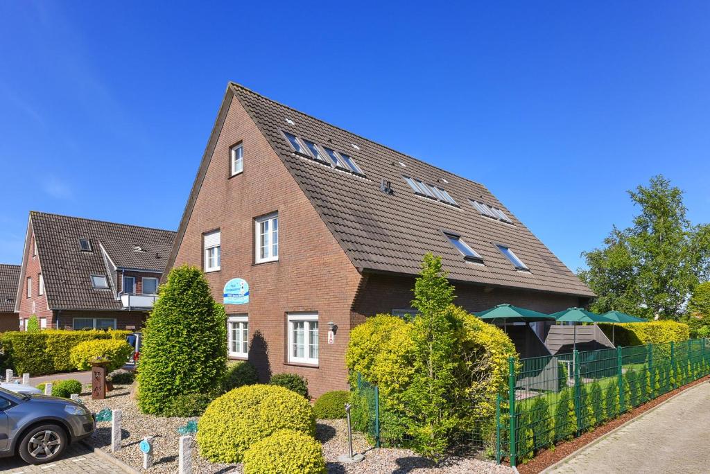 a brick house with a fence in front of it at Haus Nordseesterne in Bensersiel