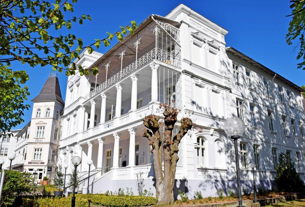 a white building with a tree in front of it at Appartementhaus Sellin in Ostseebad Sellin