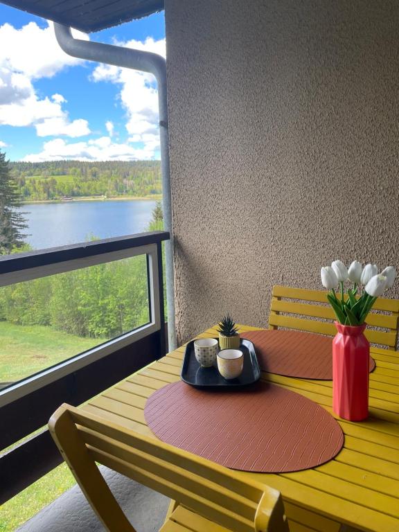 a yellow table with a vase of flowers and a window at Appartement en bord de lac in Malbuisson