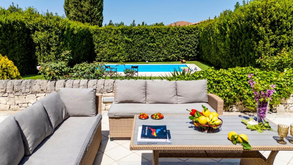 a patio with a couch and a table with fruit on it at Villa Balata di Modica con piscina privata in Ragusa